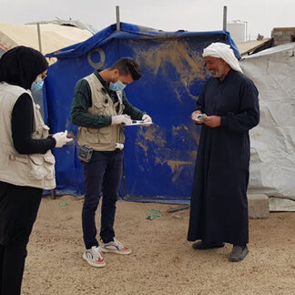 Two WFP staffers are talking with a beneficiary